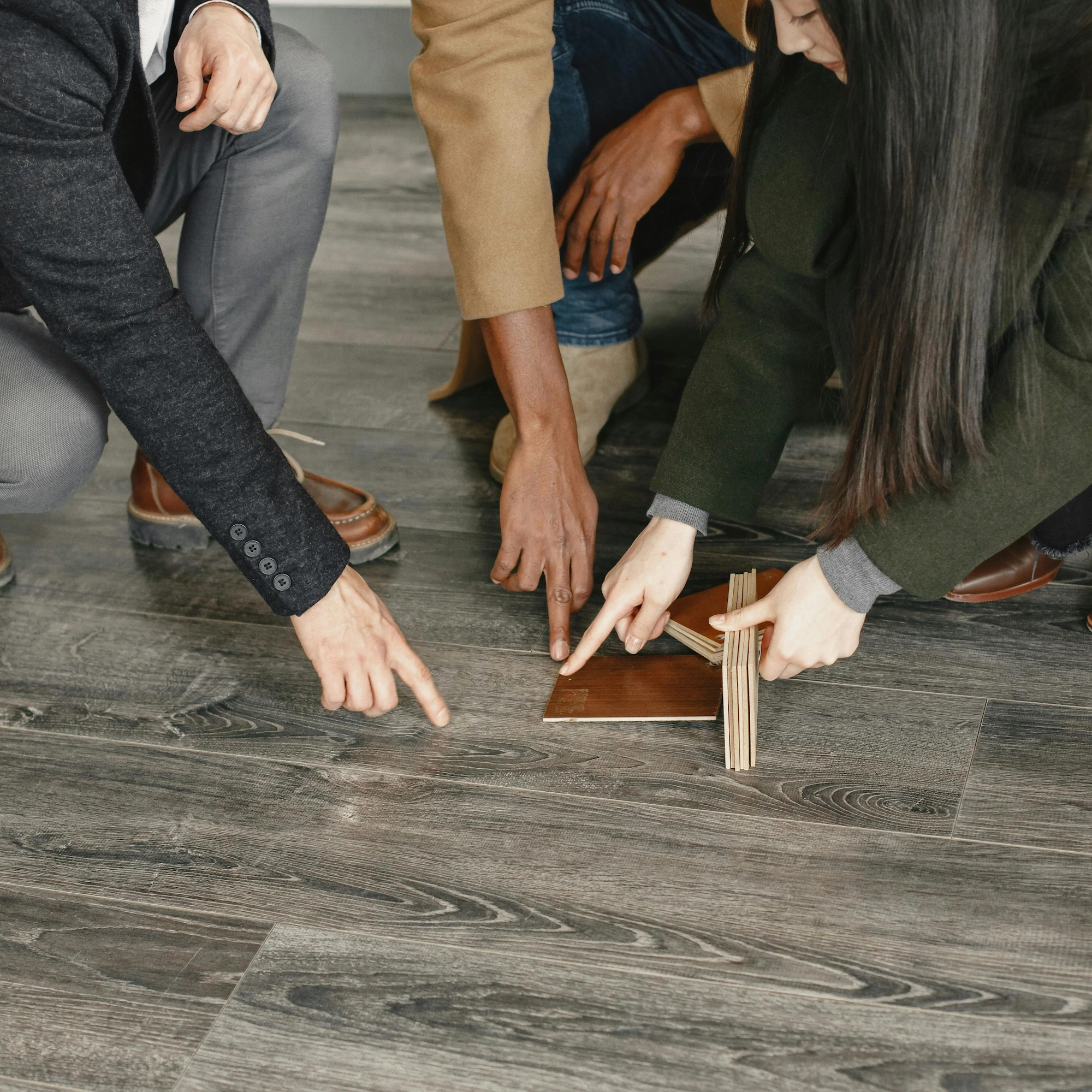 three people pointing at flooring with a sample in hand